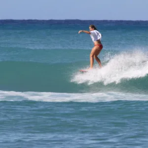 Surfers riding waves under bright sunny sky