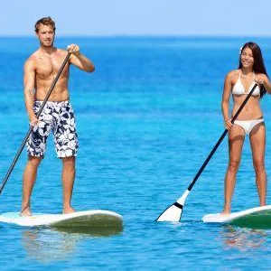 Instructor guiding a stand-up paddleboard lesson on calm water