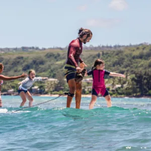 Child and instructor tandem surfing lesson