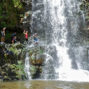 Swimmers enjoying a refreshing dip beneath a waterfall