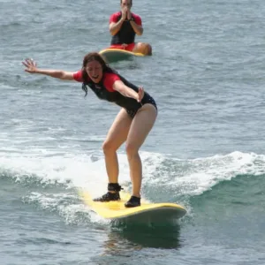 Surfing instructor helping student stand on board