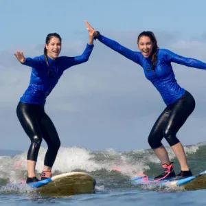 Two students learning to surf together with instructor
