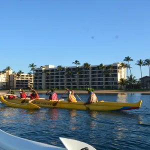 People paddling an outrigger canoe on calm water