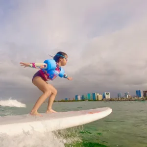 Child learning to surf on gentle Hawaiian waves