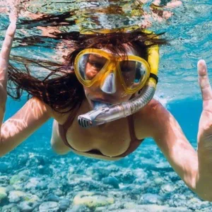 Snorkeler swimming near a Hawaiian sea turtle underwater