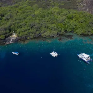 Boat cruising along rugged Hawaiian coastline