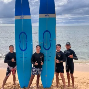 Surf instructor teaching group of beginners on beach