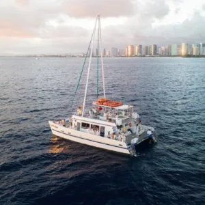 Double-decker catamaran sailing at Waikiki sunset