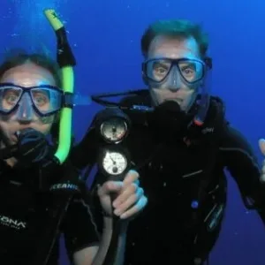 First-time diver receiving scuba instruction by coral reef