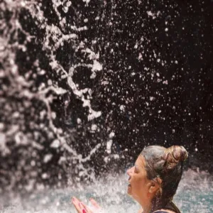 Hiker dipping feet into a refreshing waterfall pool