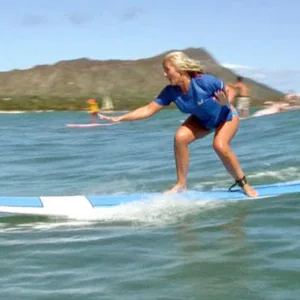 Surf instructor helping student catch wave