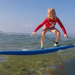 Children learning to surf in shallow water
